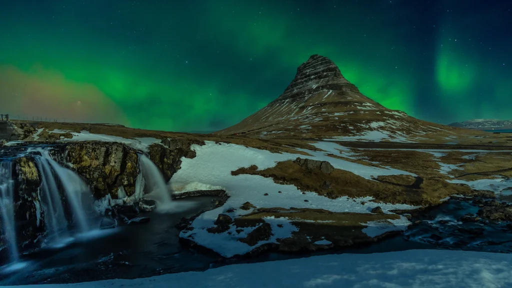 Auroras boreales sobre Kirkjufell y la cascada Kirkjufellsfoss, Islandia