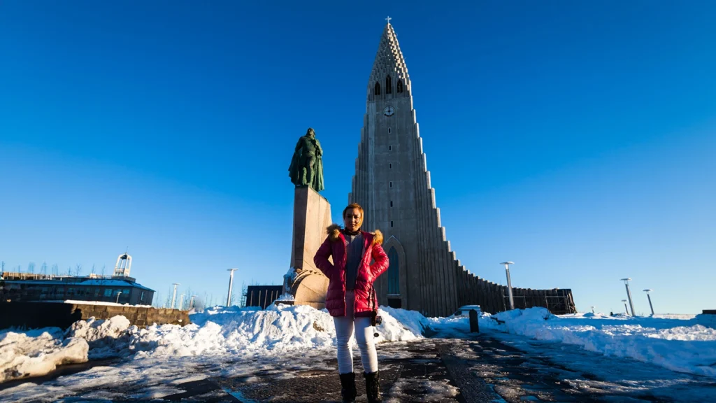 Persona frente a Hallgrímskirkja en Reikiavik (Islandia) en un día despejado de invierno