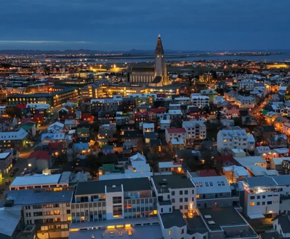 Vista aérea de Reikiavik al anochecer con Hallgrímskirkja iluminada y la bahía al fondo