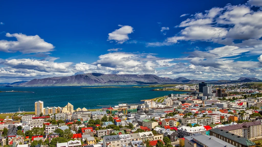 Vista panorámica de Reikiavik con la bahía y montañas al fondo en un día claro de verano