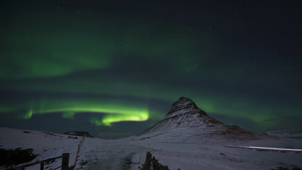 Aurora boreal sobre Kirkjufell en invierno con cielo estrellado en Islandia.