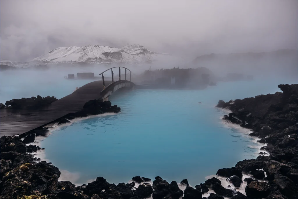 Puente de madera en Blue Lagoon con agua azul y vapor en Islandia