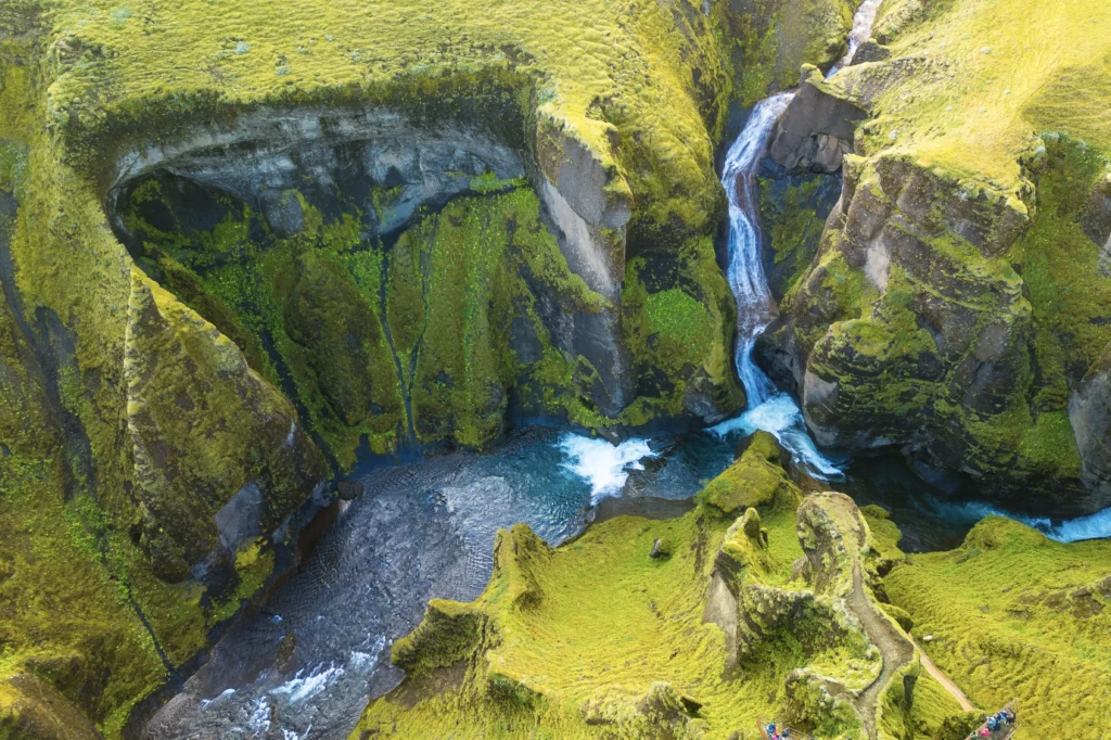 Cañón con cascada y río turquesa rodeado de musgo en Islandia