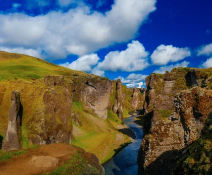 Cañón Fjaðrárgljúfur con río serpenteante y cielo azul en Islandia