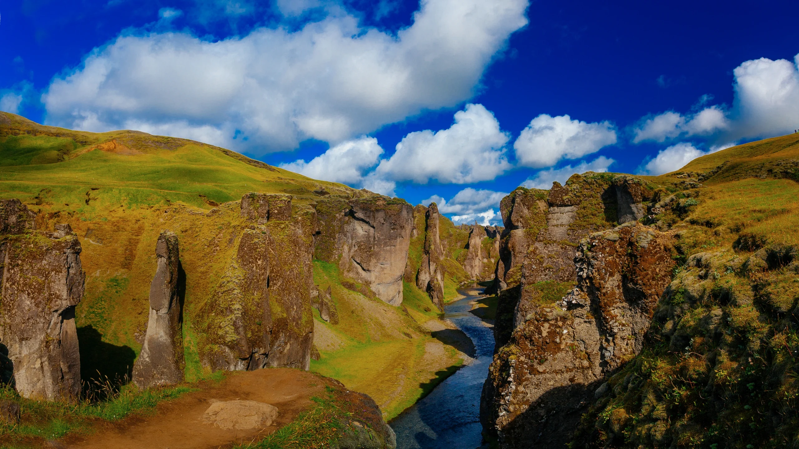 Cañón Fjaðrárgljúfur con río serpenteante y cielo azul en Islandia