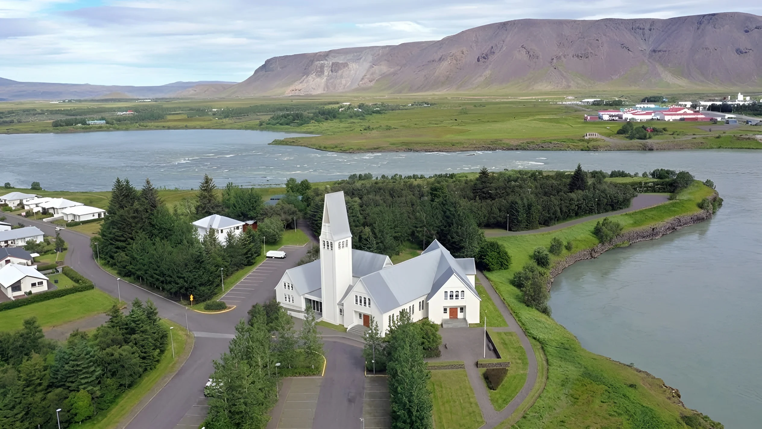 Iglesia de Selfoss junto al río Ölfusá con paisaje natural y montañas al fondo en la ciudad de Selfoss, Islandia.