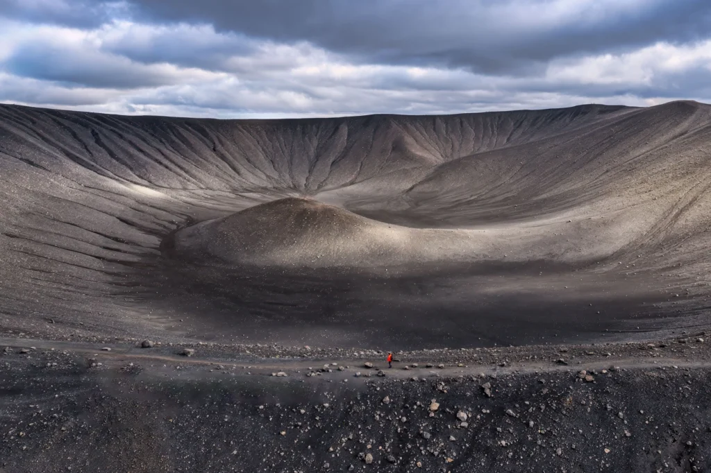 Interior del cráter del volcán Hverfjall con sendero y visitante caminando en el área del lago Mývatn, Islandia.