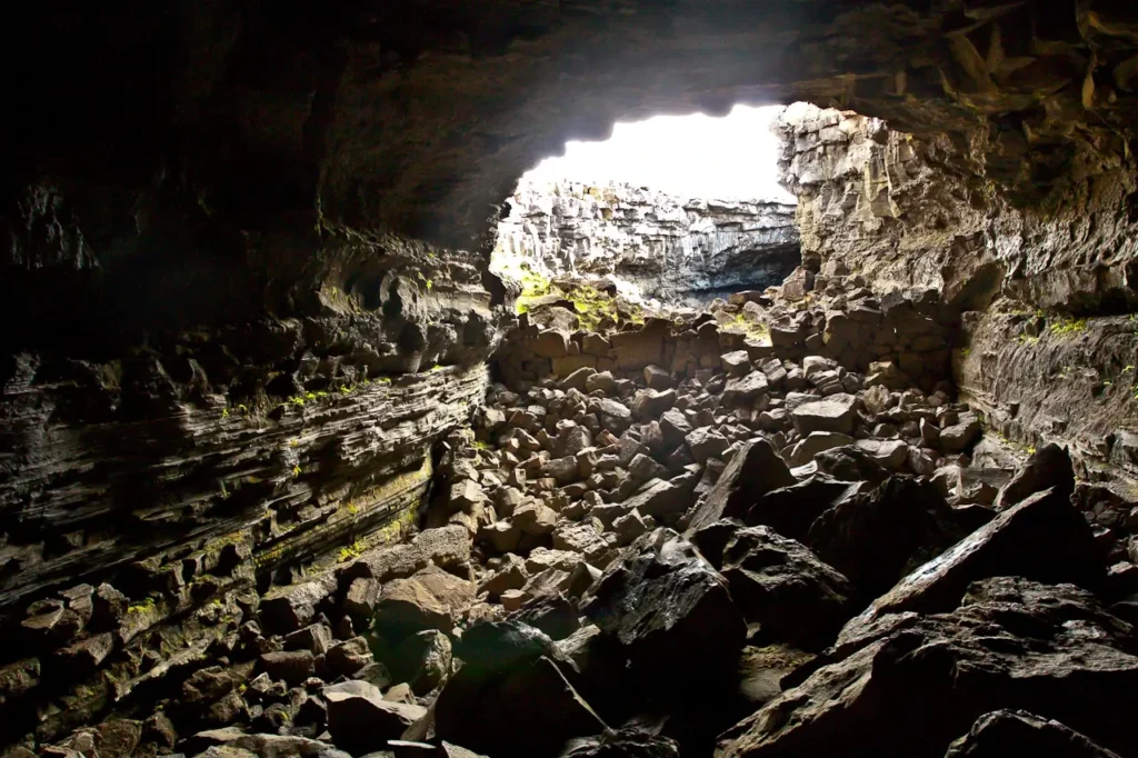 Interior de la cueva de lava Surtshellir con apertura natural y rocas volcánicas en Islandia.