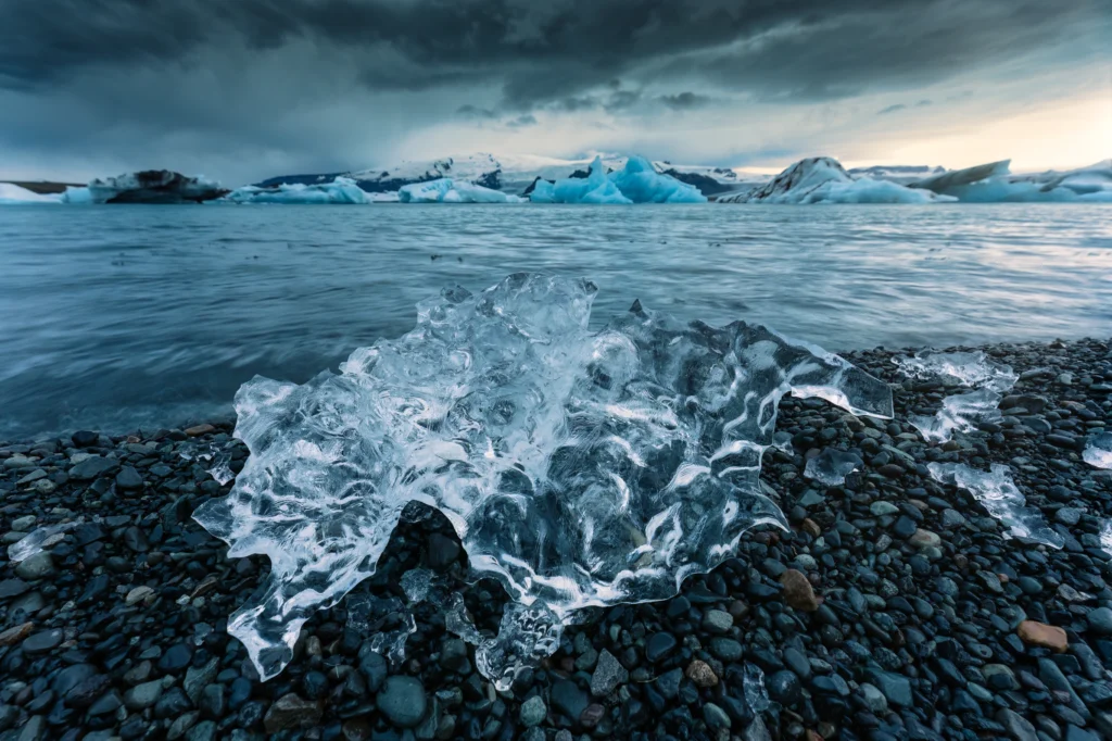 Bloque de hielo cristalino en la orilla de Jökulsárlón en Islandia con icebergs al fondo