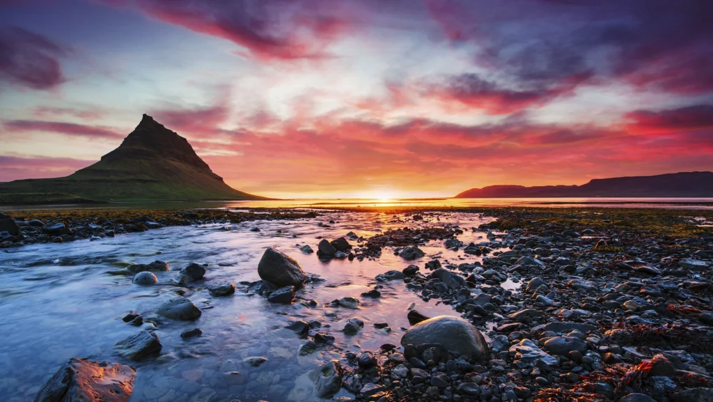 Atardecer en Kirkjufell con río y costa rocosa en la península de Snæfellsnes, Islandia.