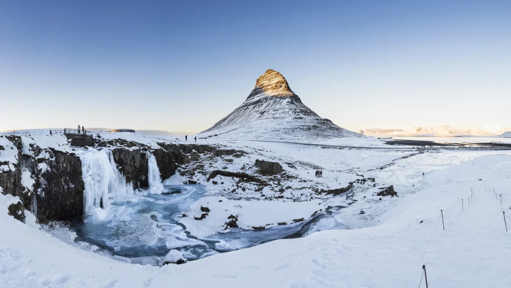 Monte Kirkjufell y cascada Kirkjufellsfoss congelada en invierno en Islandia.