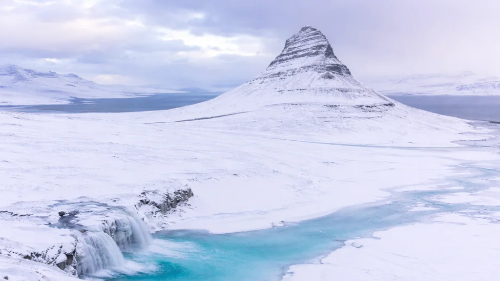 Kirkjufell y cascada Kirkjufellsfoss en invierno con paisaje nevado en Islandia.
