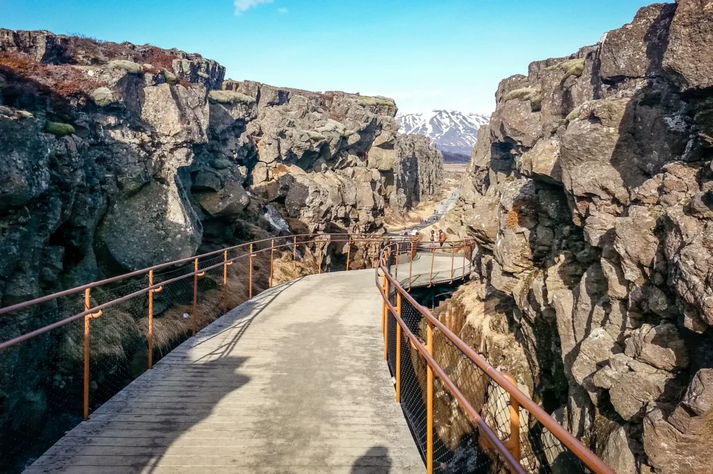 Pasarela de madera en la grieta de Almannagjá en el Parque Nacional Thingvellir entre paredes de roca volcánica.