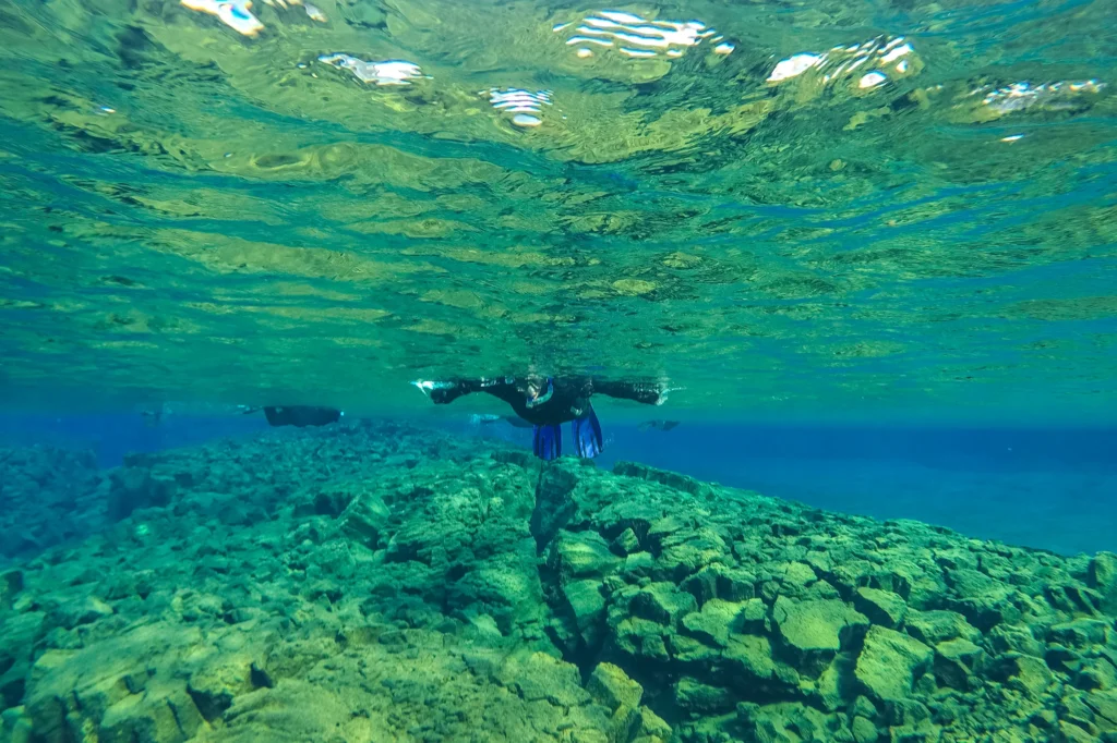Buceador haciendo snorkel en la fisura de Silfra entre placas tectónicas en Thingvellir, Islandia.