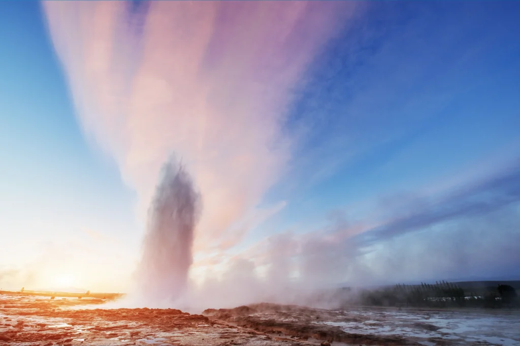 Géiser Strokkur en erupción al atardecer con cielo de colores en Islandia