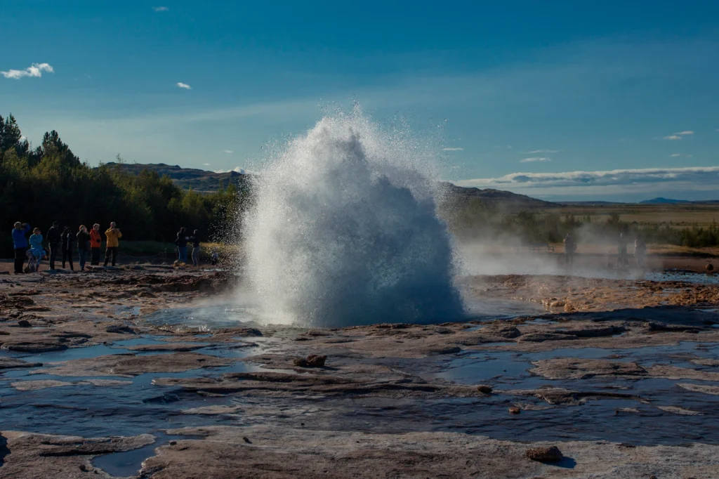 Erupción del géiser Strokkur con turistas observando en Islandia