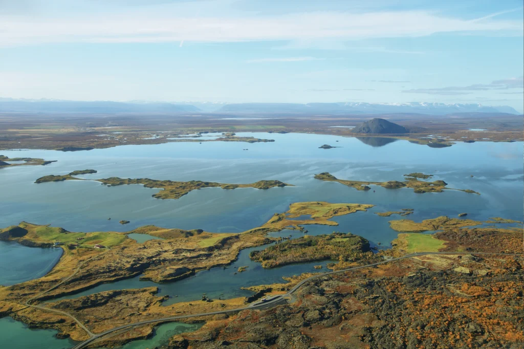 Vista aérea del lago Mývatn con sus islas volcánicas y el cráter Hverfjall al fondo en el norte de Islandia.
