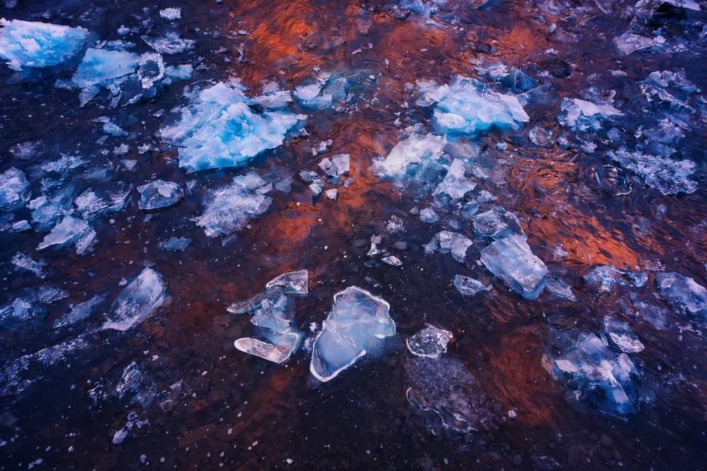 Fragmentos de hielo flotando en Jökulsárlón con reflejos cálidos al atardecer en Islandia
