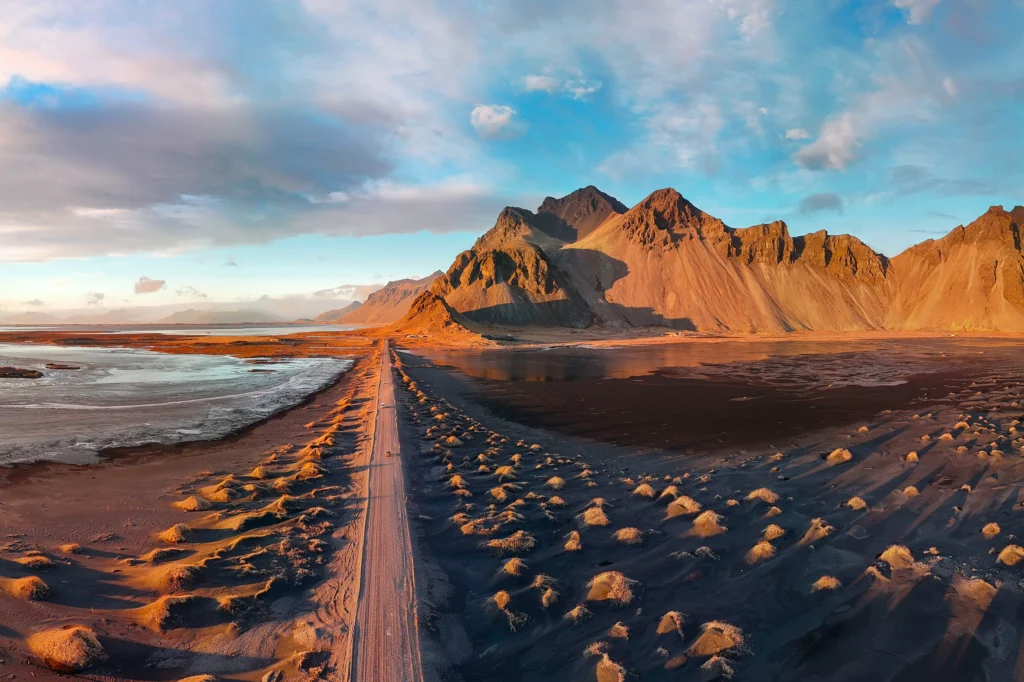 Carretera hacia Vestrahorn en Stokksnes con dunas de arena negra al atardecer en Islandia