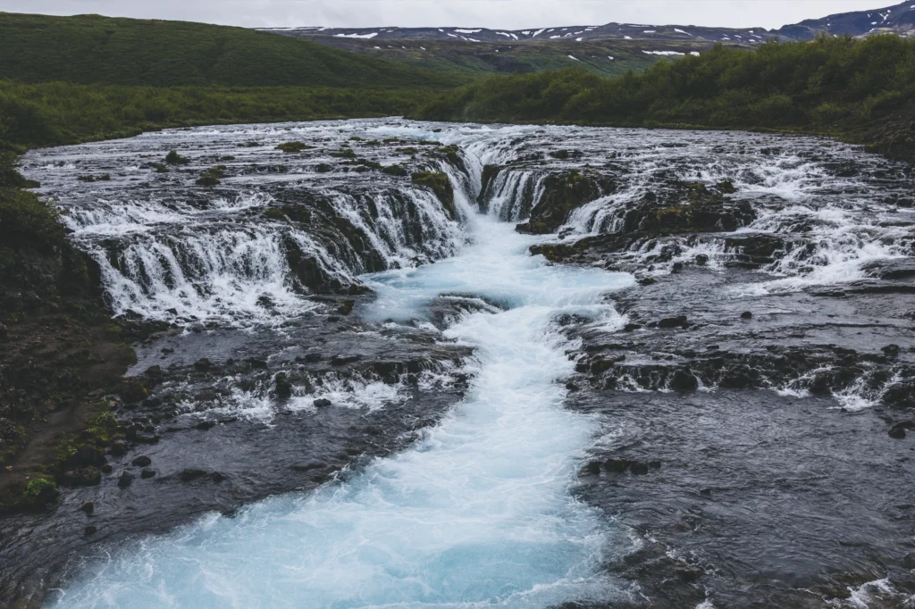 Cascada Bruarfoss con agua azul turquesa entre formaciones rocosas volcánicas en Islandia