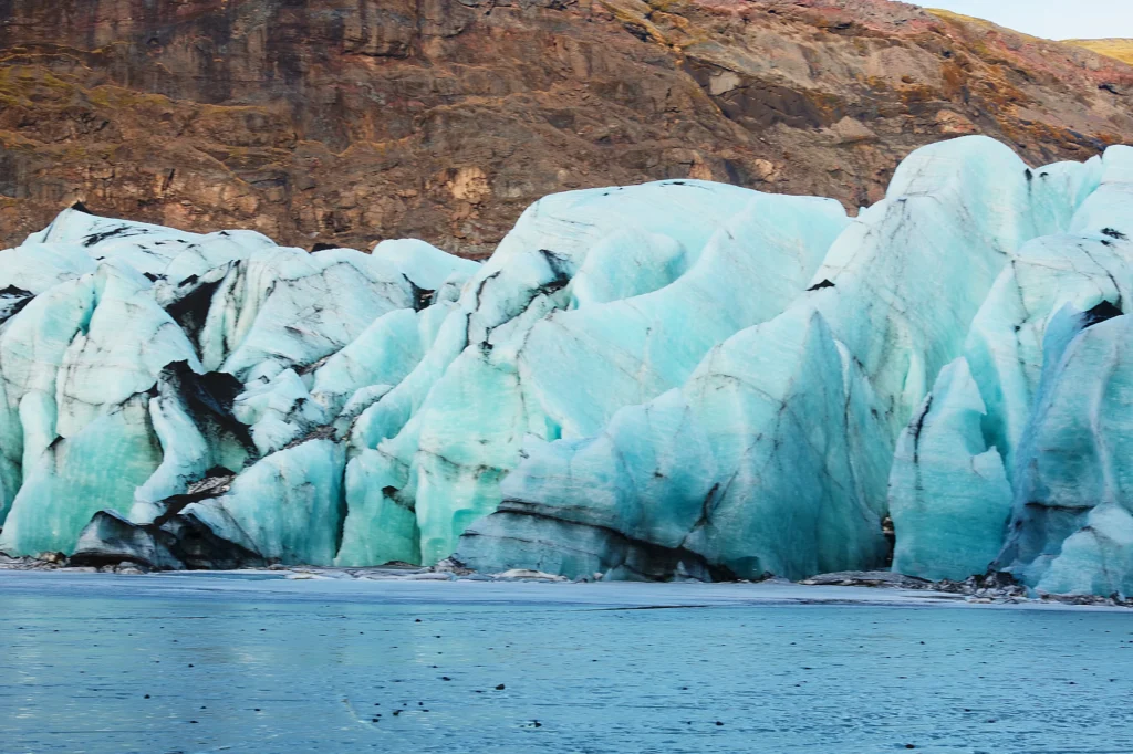 Formaciones de hielo azul del glaciar Vatnajökull con grietas y sedimentos volcánicos en Islandia