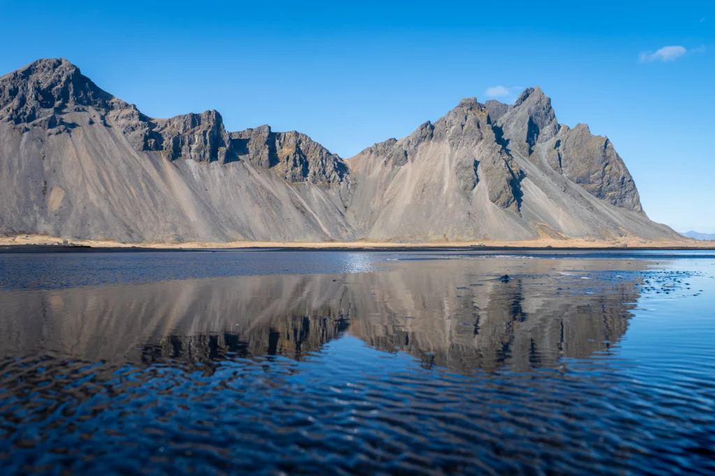 Montañas de Vestrahorn en Stokksnes reflejadas en la playa de arena negra en Islandia