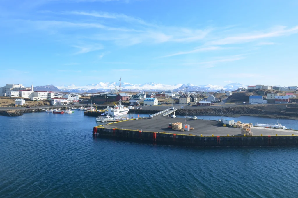 Puerto de Stykkishólmur con barcos, pueblo y montañas nevadas al fondo en Islandia