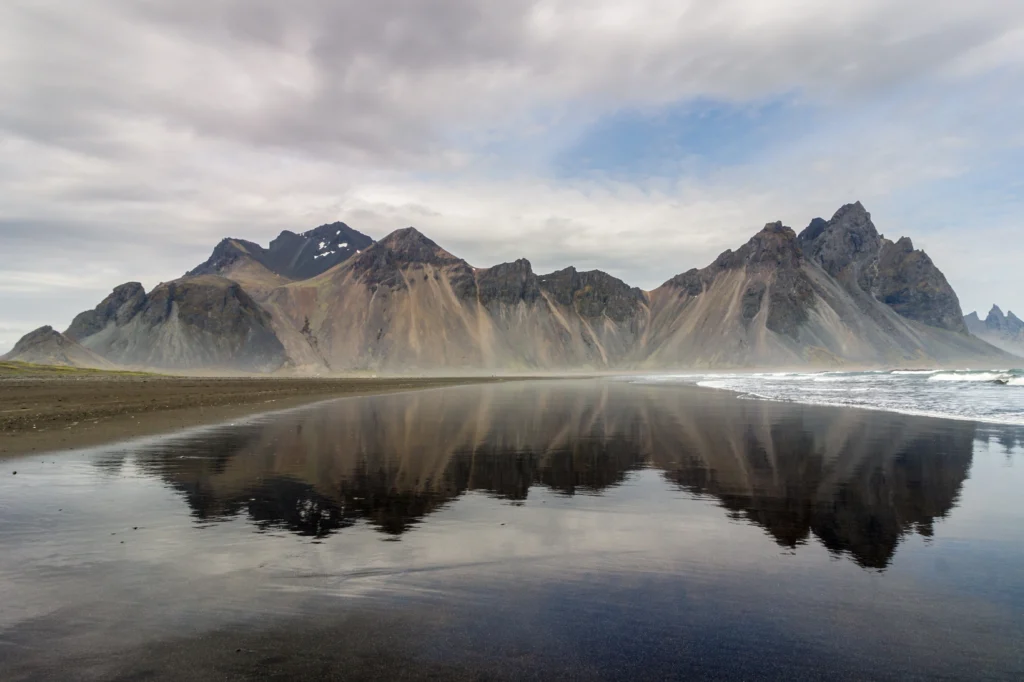 Montaña Vestrahorn reflejada en la playa de arena negra de Stokksnes en Islandia