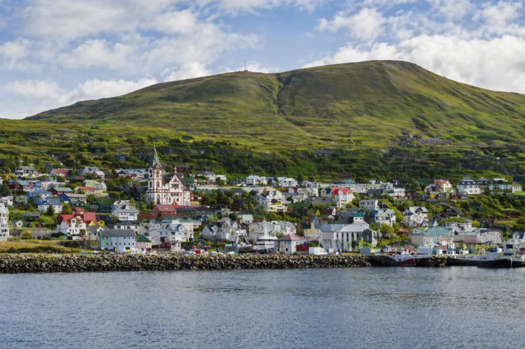 Vista de Húsavík con iglesia, casas coloridas y montaña al fondo en Islandia