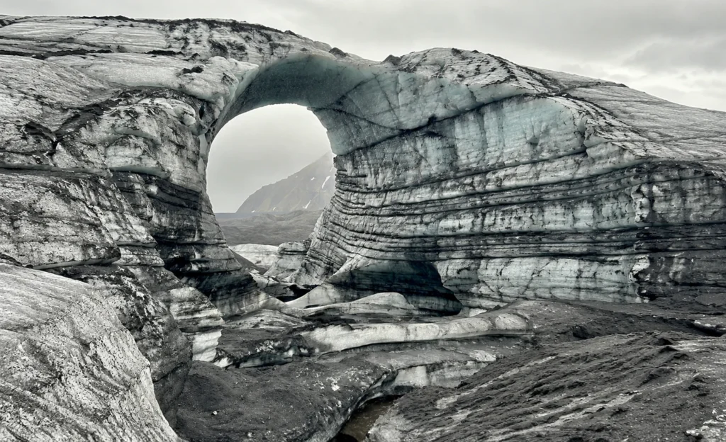 Arco natural de hielo glaciar en Katla Islandia con capas de ceniza volcánica