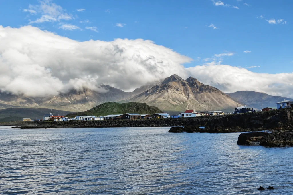 Costa de Borgarfjörður Eystri con pueblo, mar y montañas bajo nubes en Islandia