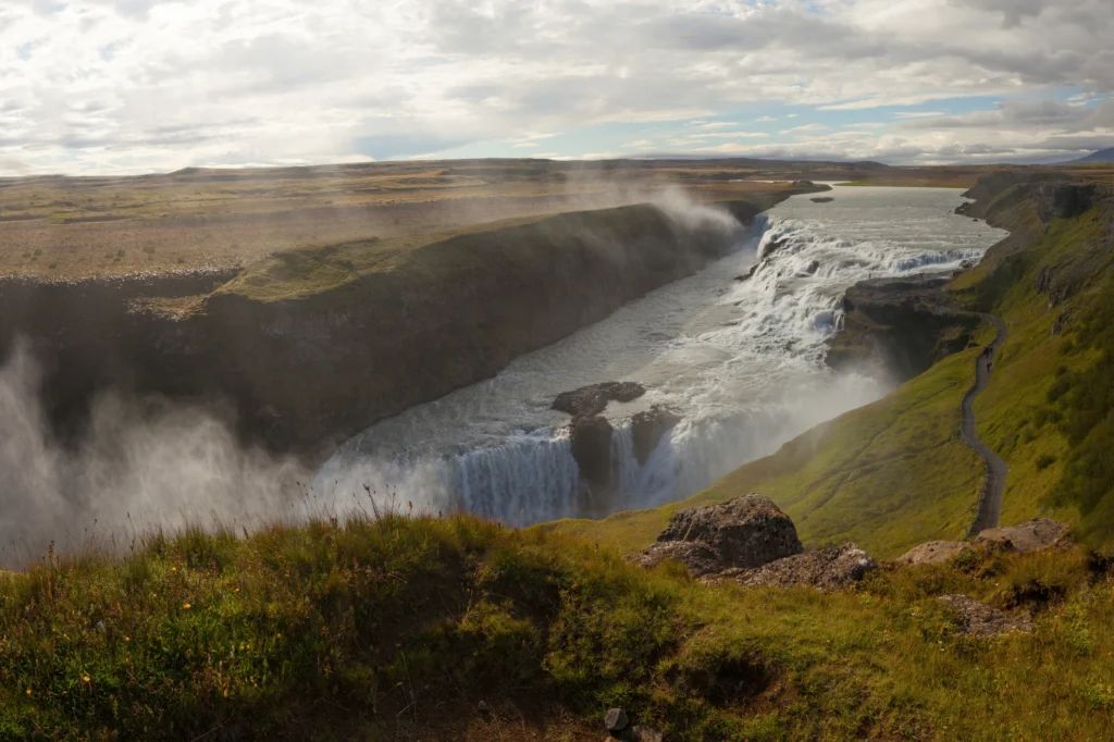 Cascada Gullfoss en Islandia con vista panorámica del cañón y sendero natural entre praderas verdes