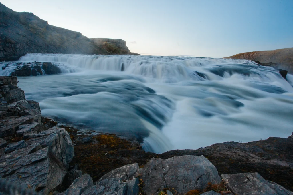 Cascada islandesa con efecto seda y larga exposición en paisaje rocoso al atardecer