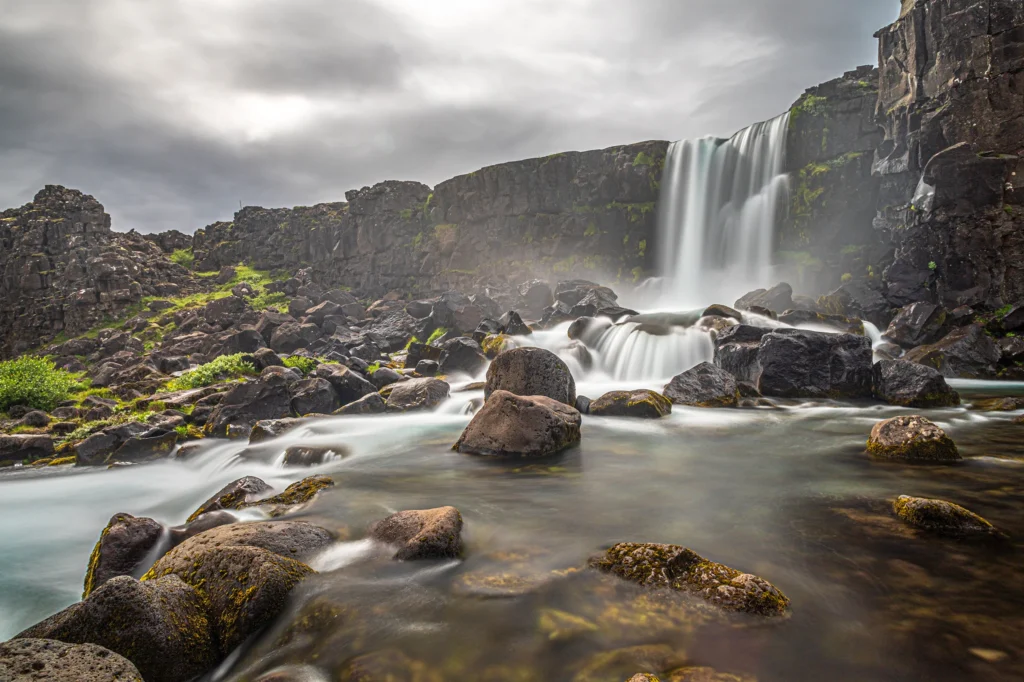 Cascada Öxarárfoss en Thingvellir con larga exposición y rocas volcánicas en primer plano
