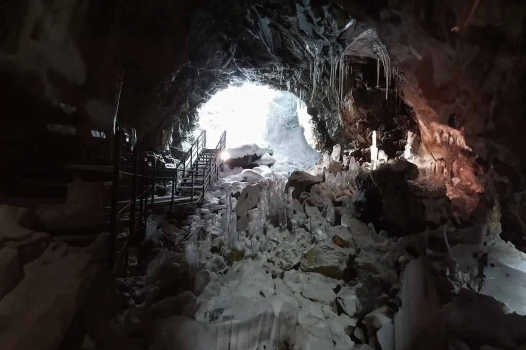 Cueva de lava Raufarhólshellir en Islandia con formaciones de hielo, estalactitas y entrada iluminada en invierno