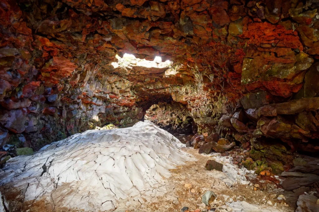 Interior de la cueva de lava Raufarhólshellir con apertura natural y formaciones de hielo en Islandia