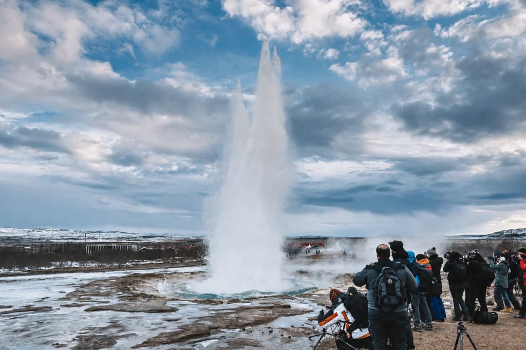 Turistas observando la erupción del géiser Strokkur en el área geotérmica de Geysir en Islandia