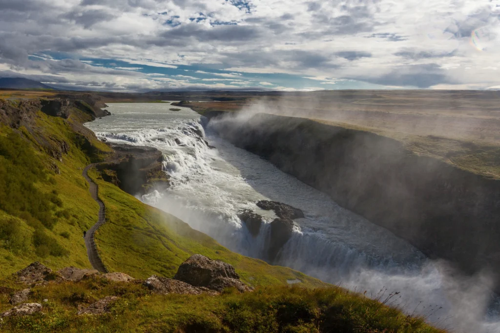 Cascada Gullfoss con bruma y cañón verde bajo cielo nublado en Islandia
