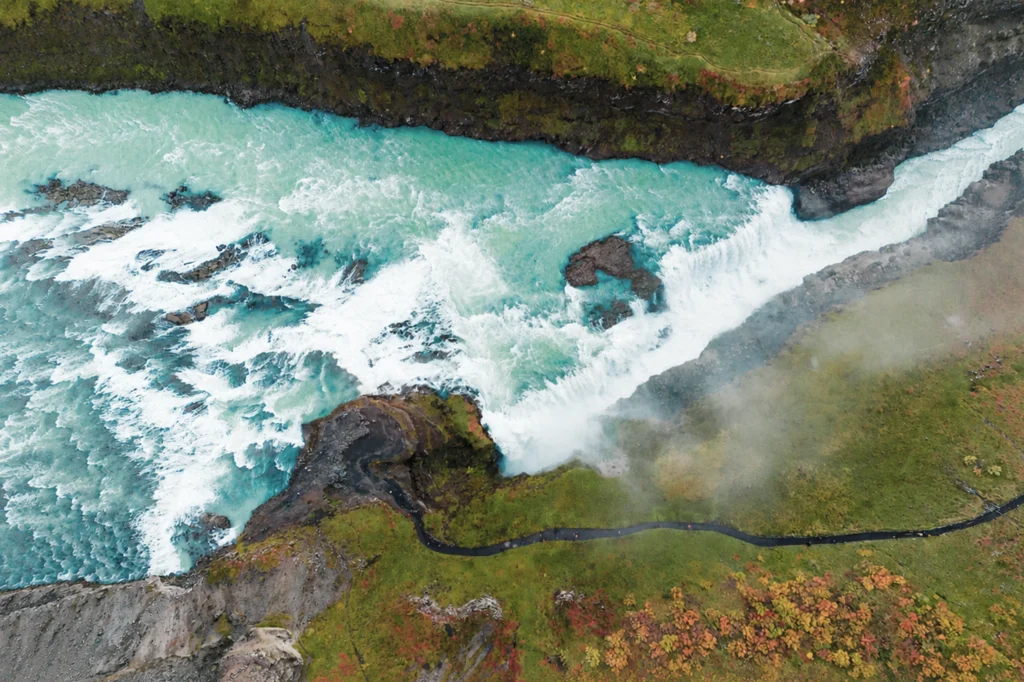 Vista aérea de la cascada Gullfoss con río turquesa y sendero en paisaje verde de Islandia
