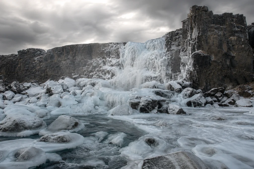 Cascada Öxarárfoss congelada en invierno con hielo y rocas en Thingvellir Islandia