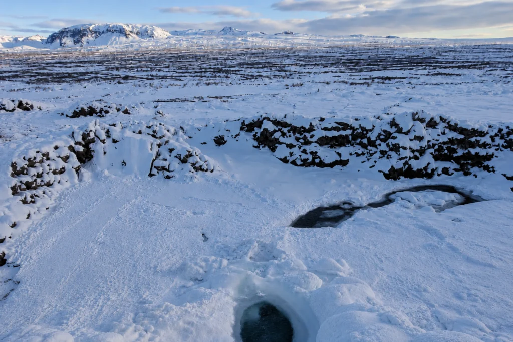 Cascada Öxarárfoss congelada en invierno en Thingvellir con paisaje nevado y río parcialmente helado