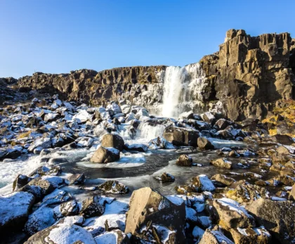 Cascada Öxarárfoss en invierno con nieve sobre rocas volcánicas en Thingvellir