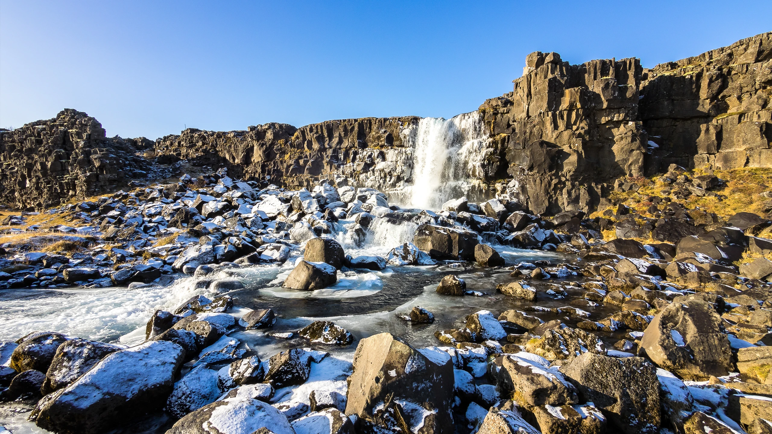 Cascada Öxarárfoss en invierno con nieve sobre rocas volcánicas en Thingvellir