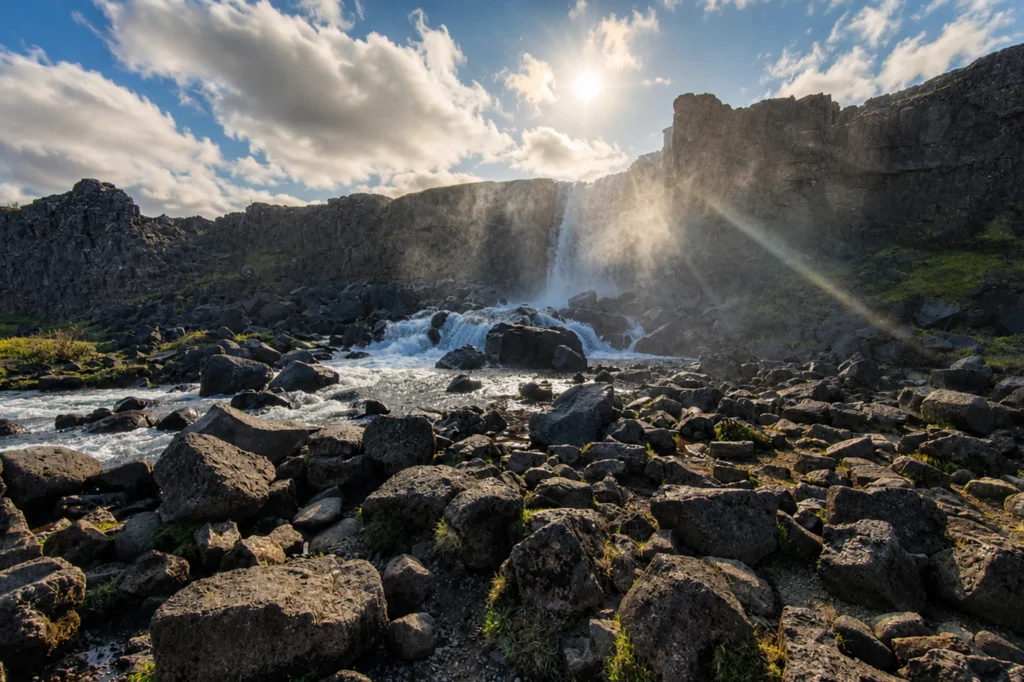 Cascada Öxarárfoss con luz solar y niebla en Thingvellir rodeada de rocas volcánicas