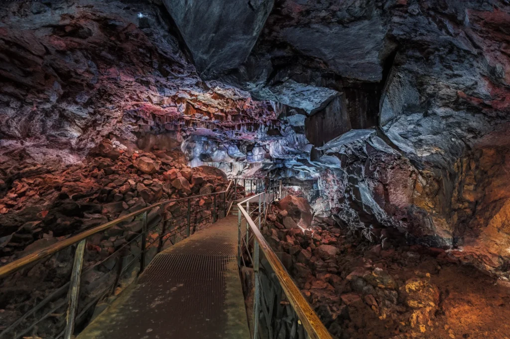 Pasarela interior en la cueva de lava Raufarhólshellir con formaciones rocosas y hielo en Islandia