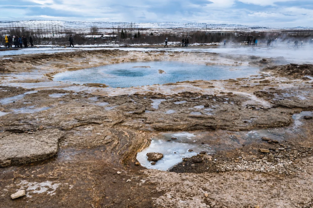 Poza geotérmica azul en Geysir Islandia rodeada de terreno volcánico y vapor