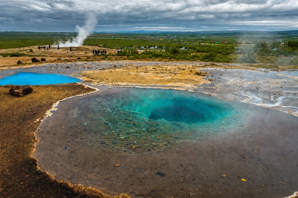 Poza geotérmica de agua azul intensa en el área de Geysir con turistas al fondo en Islandia