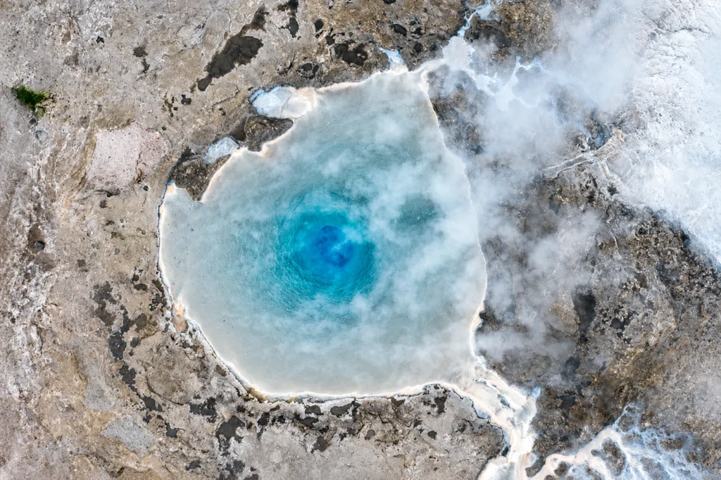 Vista aérea de poza geotérmica azul en Geysir Islandia con vapor y formaciones minerales