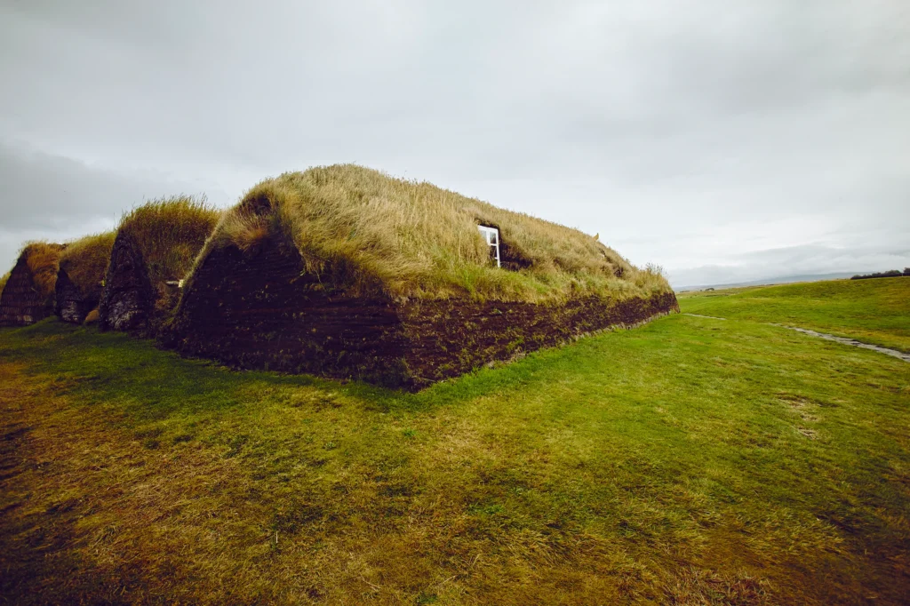 Casa tradicional islandesa de turba con techo de hierba en paisaje rural de Islandia