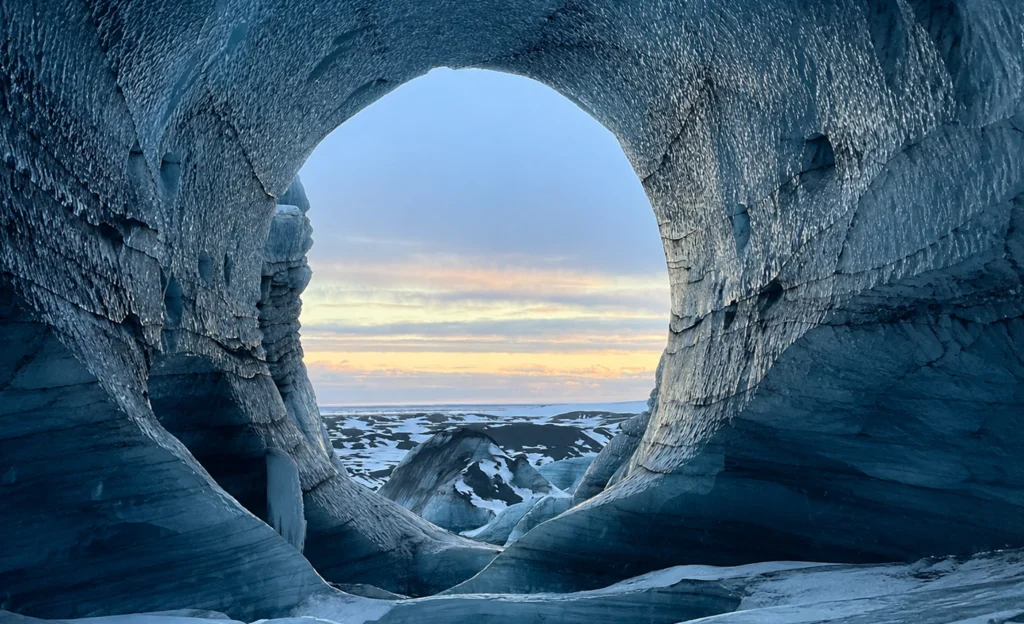 Cueva de hielo en Katla con arco circular y vista al glaciar al atardecer en Islandia